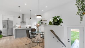 A modern kitchen with white cabinets, stainless steel appliances, and a glass dining table. - Chic Bespoke 4BR Home: King Beds&Fully Fenced Bkyd (Clarington)