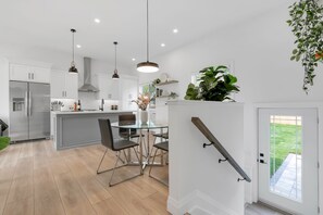 Une cuisine moderne avec des meubles blancs, des appareils en acier inoxydable et une table à manger en verre.
