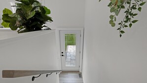 A staircase leading to a door with a view of a garden. - Chic Bespoke 4BR Home: King Beds&Fully Fenced Bkyd (Clarington)