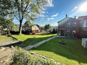 A residential backyard with a lawn, a fire pit, and a brick house. - This is the Pittsburgh View-Mt. Washington Skyline Escape! (Pittsburgh)