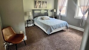 A bedroom with a bed, a chair, a nightstand, a ceiling fan, and a window with curtains. - This is the Pittsburgh View-Mt. Washington Skyline Escape! (Pittsburgh)