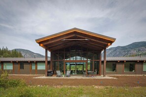 A modern building with a large glass facade, outdoor seating area, and a mountainous backdrop. - Elsie's Hut: Mazama Cabin with Big Mountain Views (Mazama)
