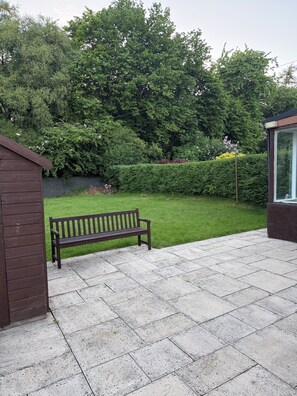 Un espace extérieur aménagé avec un banc, une structure en bois et une haie.