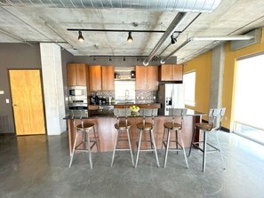 A modern kitchen with a central island, bar stools, and stainless steel appliances. - Industrial Loft · Walk to Westport · Sleeps 6 (Kansas City)