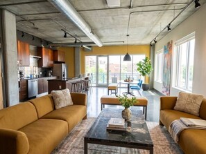 A modern interior with a sofa set, a coffee table, and a dining area with chairs and a table. - Industrial Loft · Walk to Westport · Sleeps 6 (Kansas City)