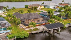 A waterfront property with a large house, a swimming pool, and a dock. - Peace River Retreat | Riverfront + Heated Pool (Punta Gorda)