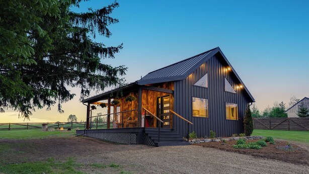 Une maison moderne avec une façade en bois, un porche et une pelouse bien entretenue.