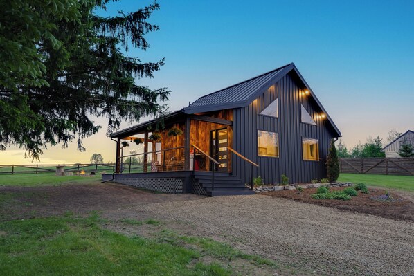 A modern house with a wooden exterior, a porch, and a well-maintained lawn.