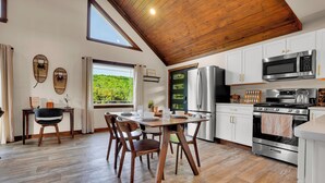 Une cuisine avec un plancher en bois, des armoires blanches, un four en acier inoxydable et un four à micro-ondes.