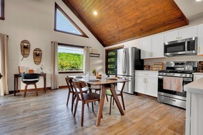 A kitchen with wooden flooring, white cabinets, a stainless steel oven, and a microwave.