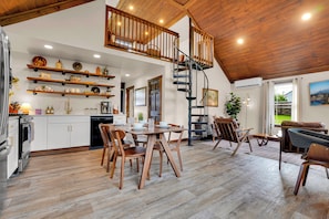 Une cuisine spacieuse avec des meubles en bois, un coin repas avec une table et des chaises en bois, un escalier en colimaçon et une vue sur lâextĂ©rieur.