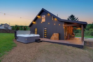 A modern building with a hot tub, wooden deck, and a covered outdoor seating area.