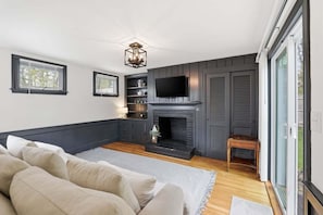 Ein modernes Wohnzimmer mit Kamin, Fernseher und einer Couch.