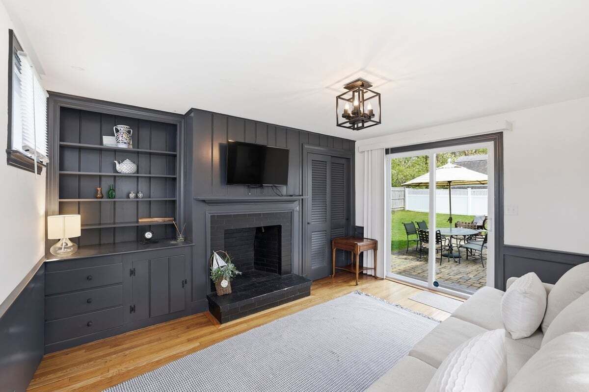 A living room with a fireplace, a television, and a sliding glass door leading to an outdoor patio.