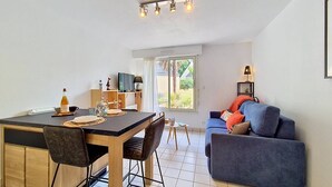 Ein modernes Wohnzimmer mit Essbereich, einer Couch und einem Fernseher.