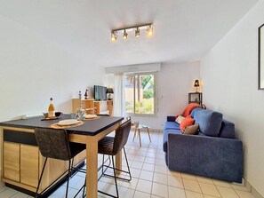 Ein modernes Wohnzimmer mit Essbereich, einer Couch und einem Fernseher.