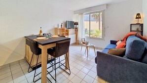 Ein modernes Wohnzimmer mit Essbereich, einer Couch, einem Fernseher und einem Fenster mit Blick.