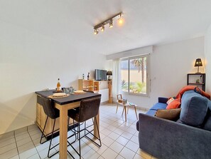 Ein modernes Wohnzimmer mit Essbereich, einer Couch, einem Fernseher und einem Fenster mit Blick.