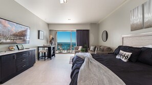 Ein modernes Schlafzimmer mit Bett, Schreibtisch und einem Balkon mit Meerblick.
