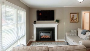 A living room with a fireplace, a sofa, a television, and a painting on the wall.