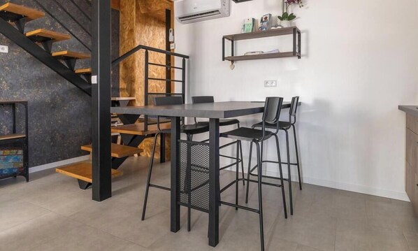 Eine moderne Küche mit einer Holztreppe, einem Esstisch mit Stühlen und eingebauten Regalen.