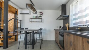 Cozinha moderna com área de refeições, detalhes em madeira e forno embutido.