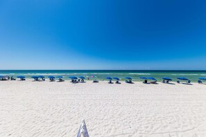 Uma praia com fileiras de guarda-sóis azuis e cadeiras de praia.