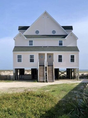 Ein zweistöckiges Haus mit Veranda, Garage und Blick auf den Strand.