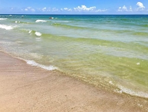 Ein Strand mit klarem Wasser und sandigem Ufer.