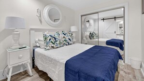 A bedroom with a bed, two bedside tables, a mirror, a wardrobe, and a small bedside lamp. - Harbor View Suite C in Historic Georgetown (Georgetown)