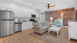 A modern kitchen with white cabinets, stainless steel appliances, and a brick accent wall. - Harbor View Suite C in Historic Georgetown (Georgetown)
