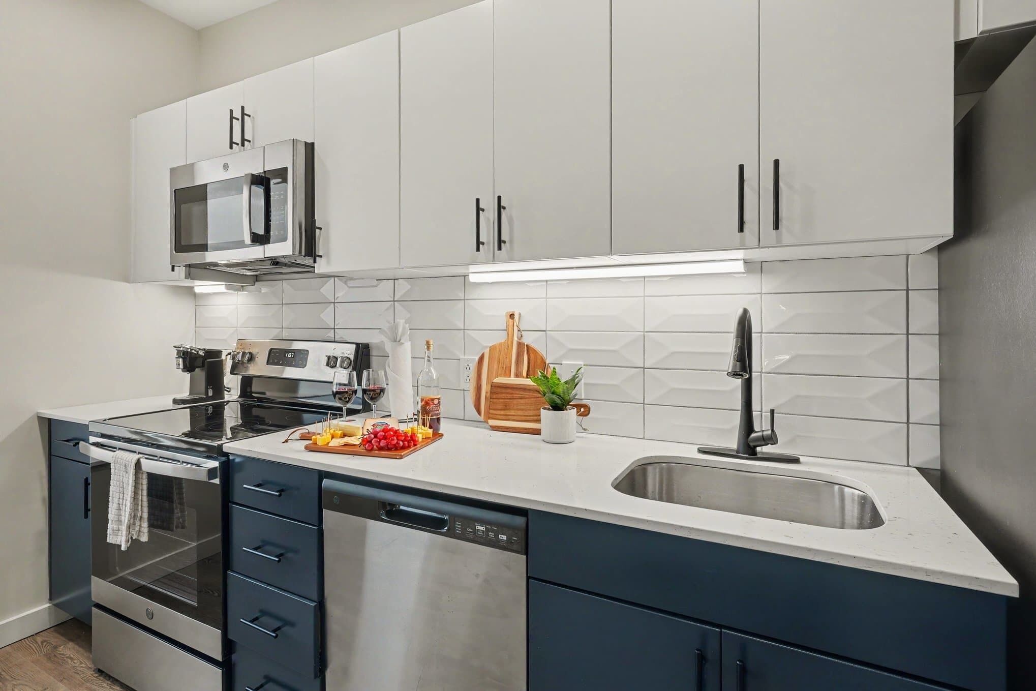 A modern kitchen with white cabinets, a stainless steel microwave, a built-in oven, and a dishwasher.