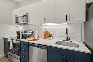 A modern kitchen with white cabinets, a stainless steel microwave, a built-in oven, and a dishwasher. - Cadence - Pool - Gym - Mins to Broadway (Nashville)