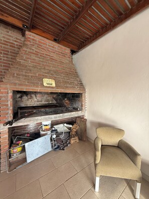 A brick fireplace with a sign, a chair, and various items on the floor.