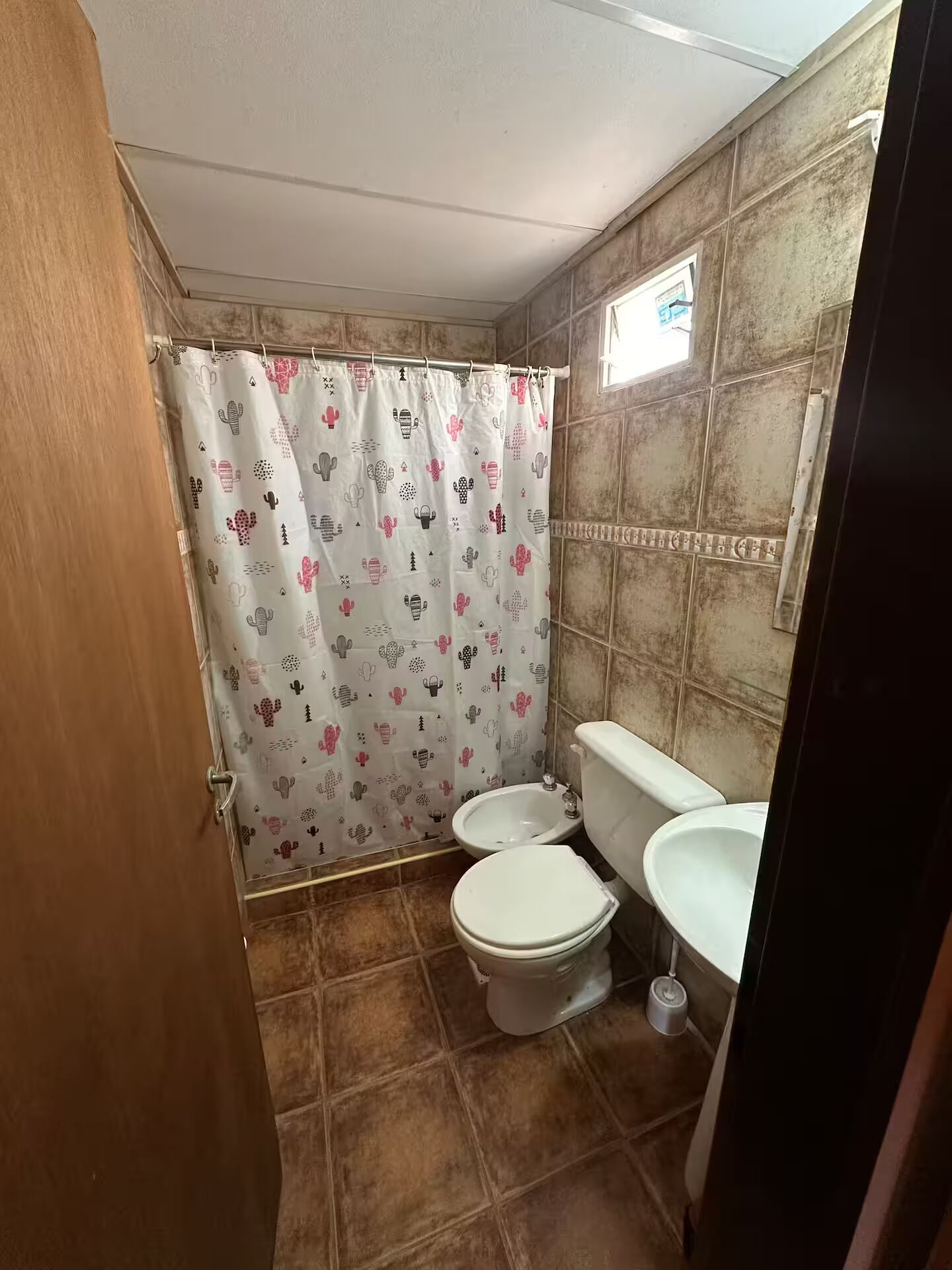 Un baño con cortina de ducha, inodoro, bidé y paredes de azulejos.