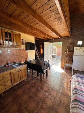 Una cocina rústica con armarios de madera, una mesa de comedor y un refrigerador.