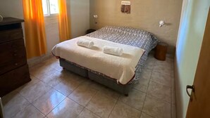 A bedroom with a bed, wooden ceiling beams, a window with curtains, and a dresser. - Potrerillos Our Roots C4 (Las Vegas)