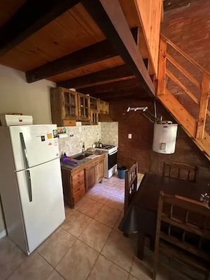 A kitchen with wooden cabinets, a refrigerator, a stove, and a dining table.