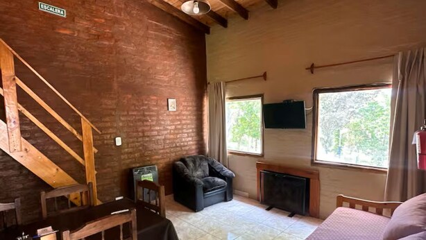 A rustic room with a wooden staircase, a fireplace, a sofa, and a dining table. - Potrerillos Our Roots C4 (Las Vegas)