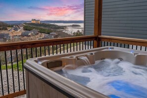 Un jacuzzi en un balcón con vistas a un edificio lejano y al paisaje.