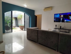 A living room with a TV, a sofa, and a potted plant.