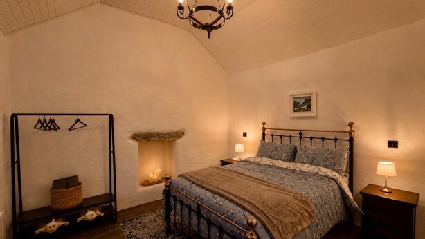 Ein Schlafzimmer mit einem Bett, Nachttischen, einer Hängeleuchte, einem Kamin und einem Wandbild.