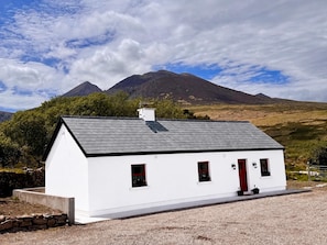 A white building with a red door, a chimney, and a small window.