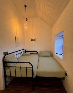 A small room with two beds, a window, a light fixture, and a picture on the wall. - Cottage Sleeps 4 With Parking (Killarney)
