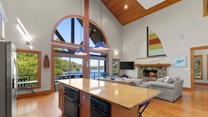 A modern kitchen with a central island, a dining area with a view, and a cozy seating area with a fireplace. - Mi Casa, Su Casa | Fire Pit | Dock | Game Rom | Sleeps 14 (Sherrills Ford)