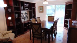 Un comedor con una mesa y sillas, rodeado de estanterías de madera con diversos objetos.