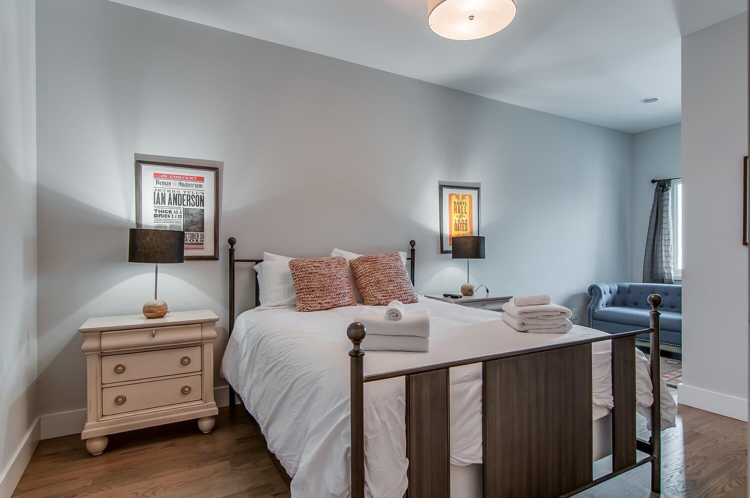 Une chambre à coucher avec un lit, des tables de chevet, une commode et un canapé bleu.