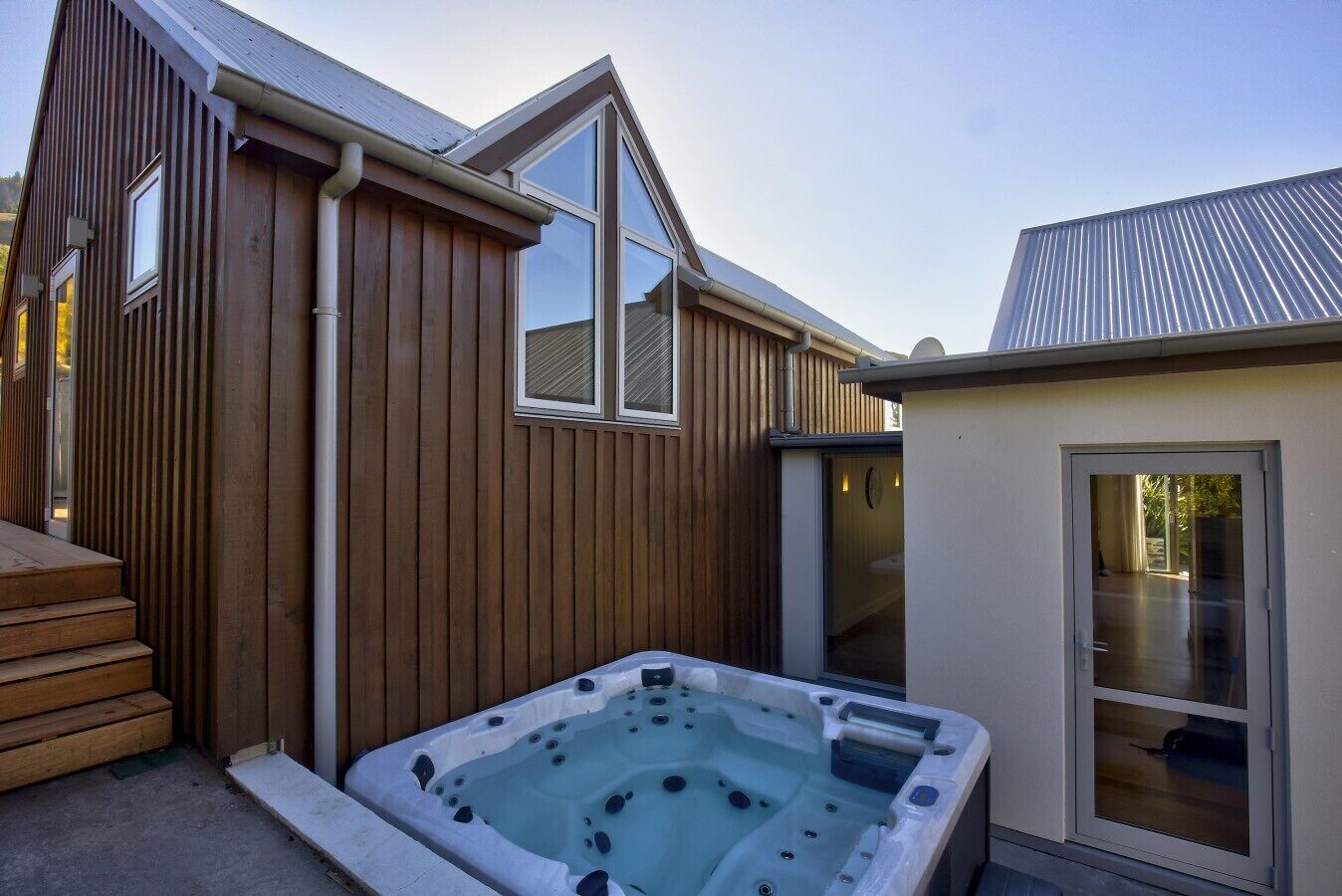 Une maison en bois dotée d’un jacuzzi, d’un patio couvert et d’une porte-fenêtre coulissante.