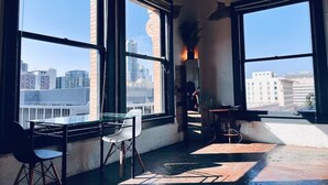 A room with large windows, a glass table, a chair, a small table with a plant, and a mirror. - Massive Loft Penthouse w best views in Prime DTLA (Los Angeles)