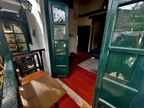 Un couloir étroit avec un banc en bois et une porte verte.